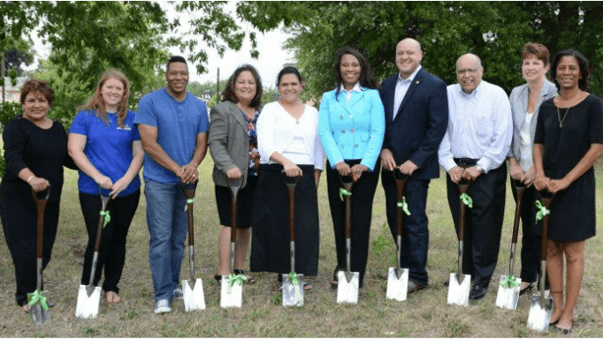 A row of people holding shovels at a groundbreaking ceremony