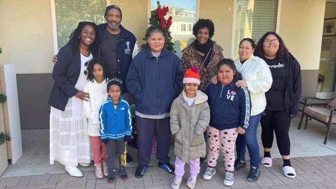 A family with children standing together on a front porch decorated for the holidays