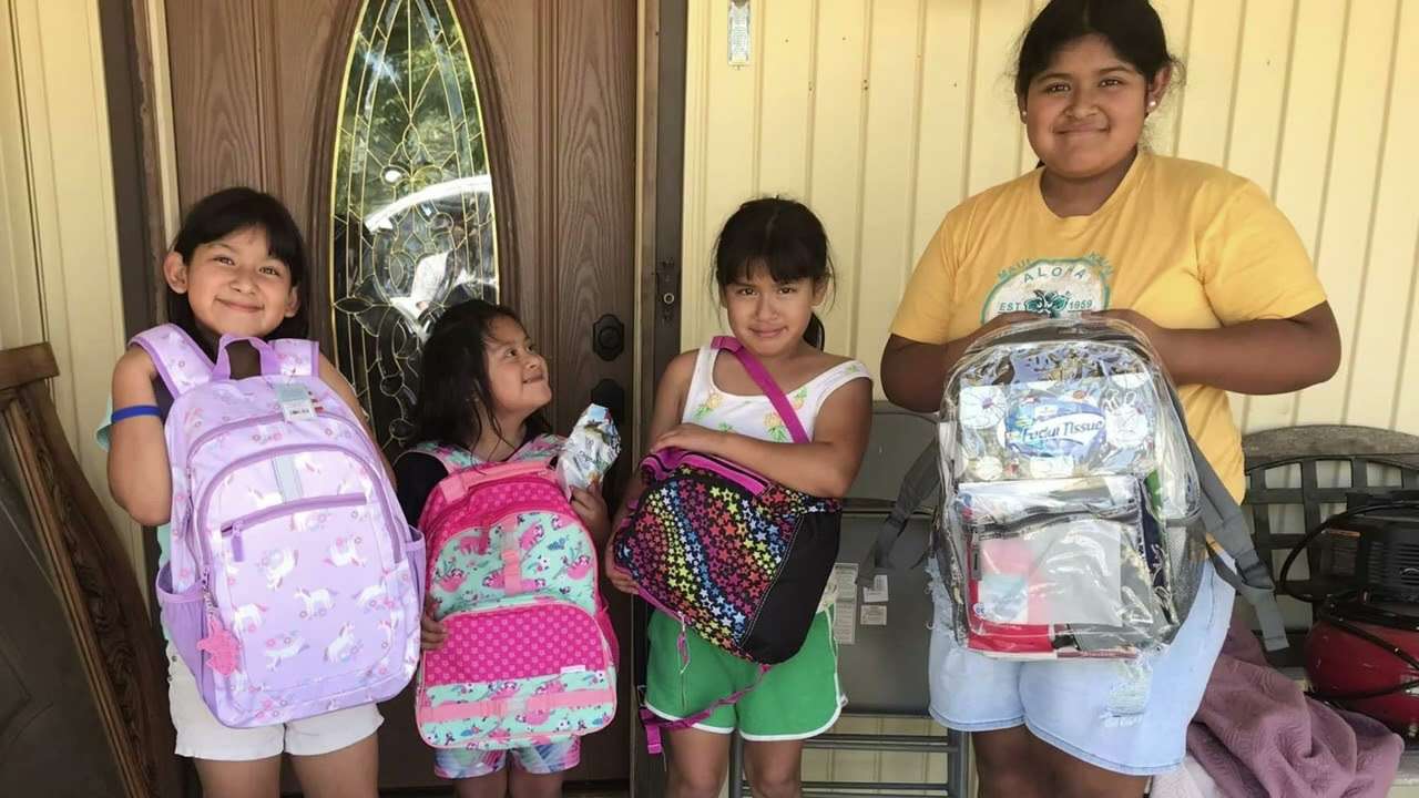 Four girls showing their new school backpacks on a front porch