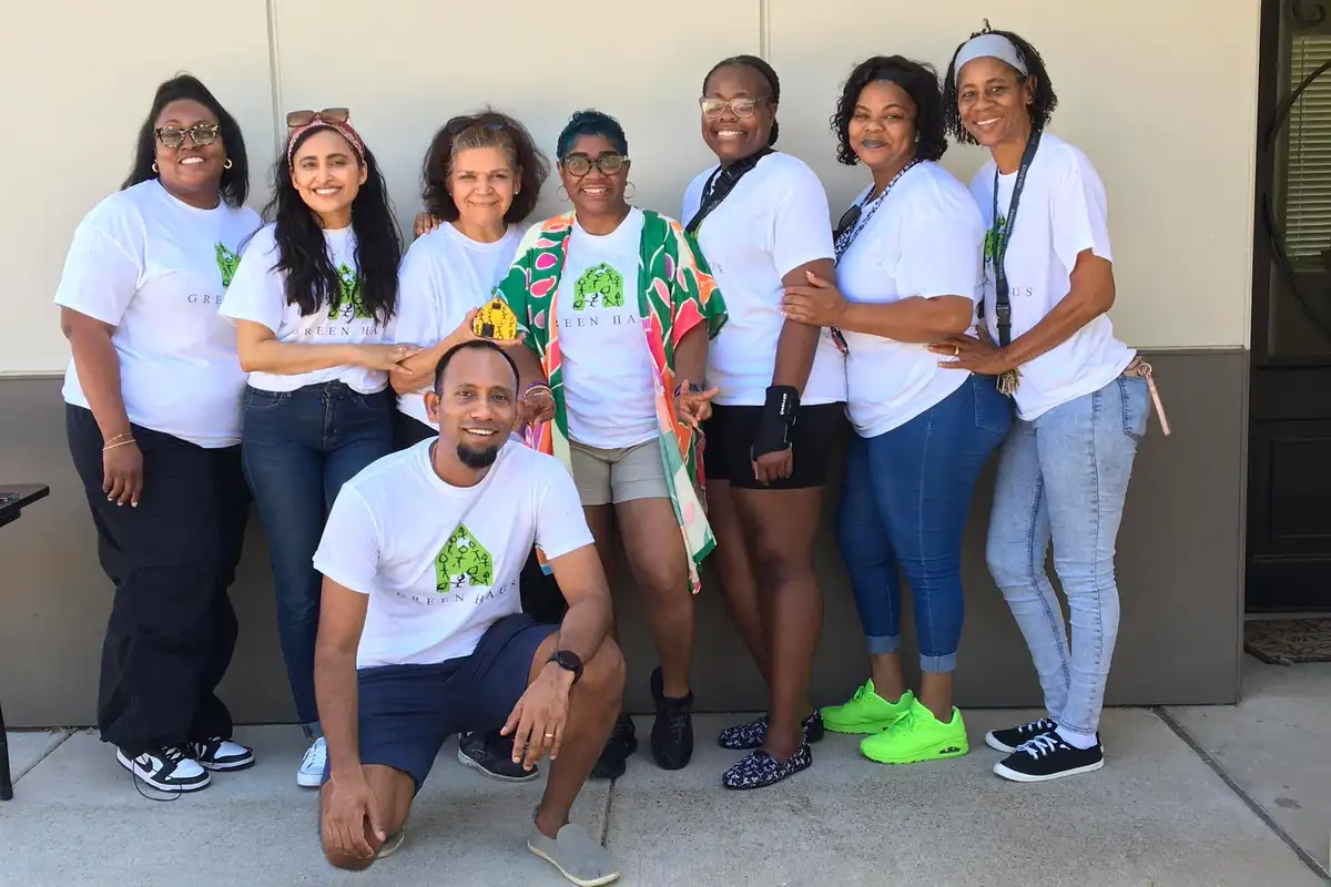 Staff and volunteers in white Shared Housing T-shirts posing together outside