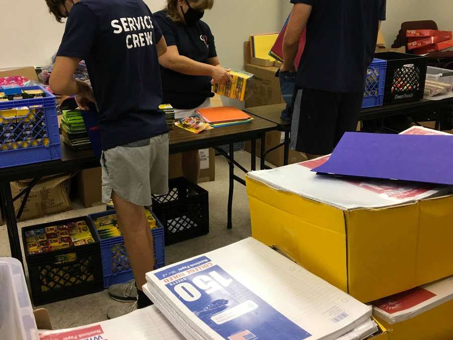 Volunteers sorting donated school supplies on tables